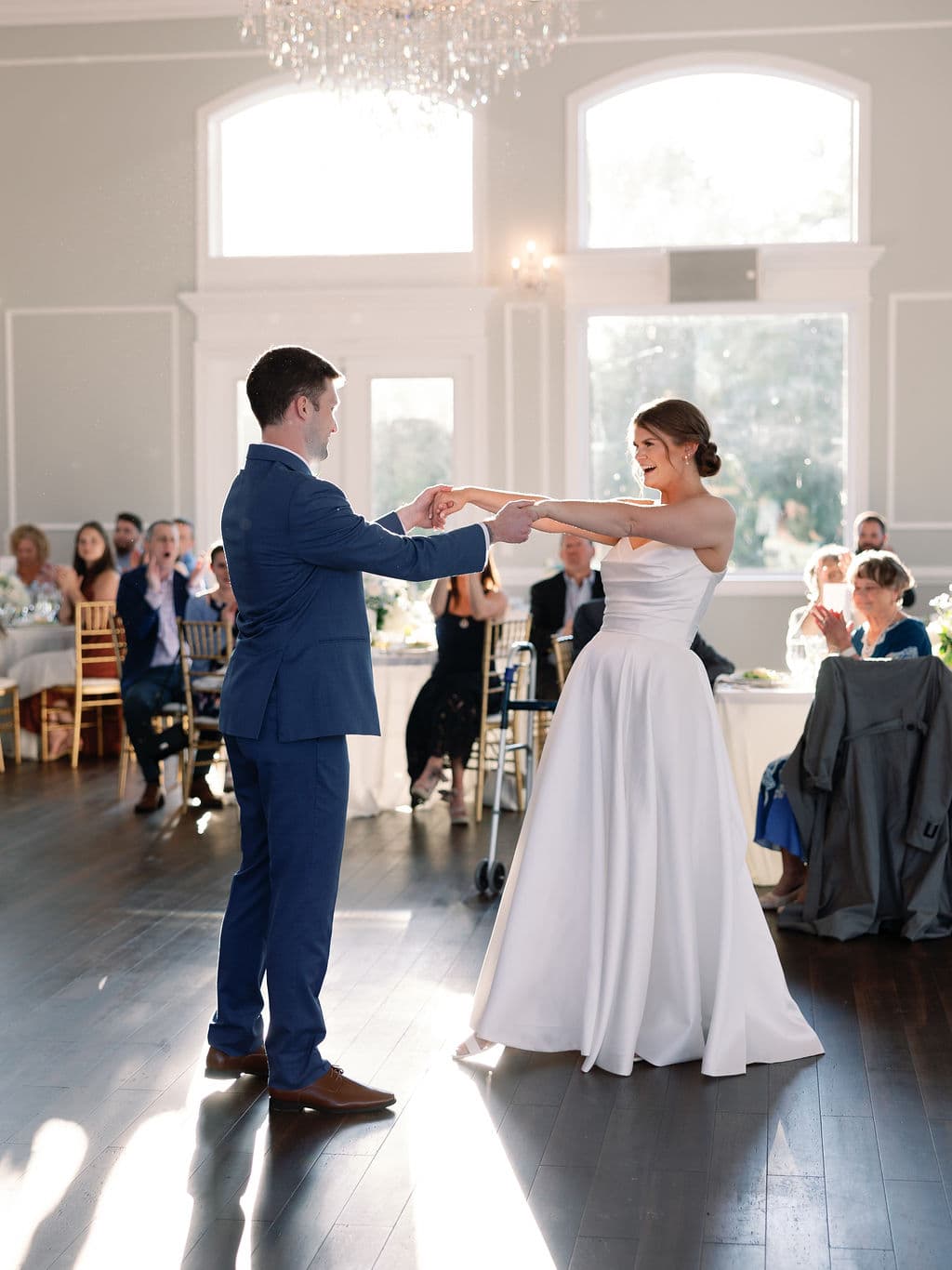 First dance beneath the chandelier in the sunlit ballroom