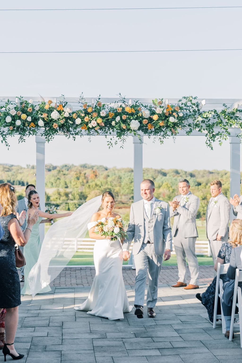 Newlyweds' recessional beneath an orange floral pergola with the Virginia hills beyond